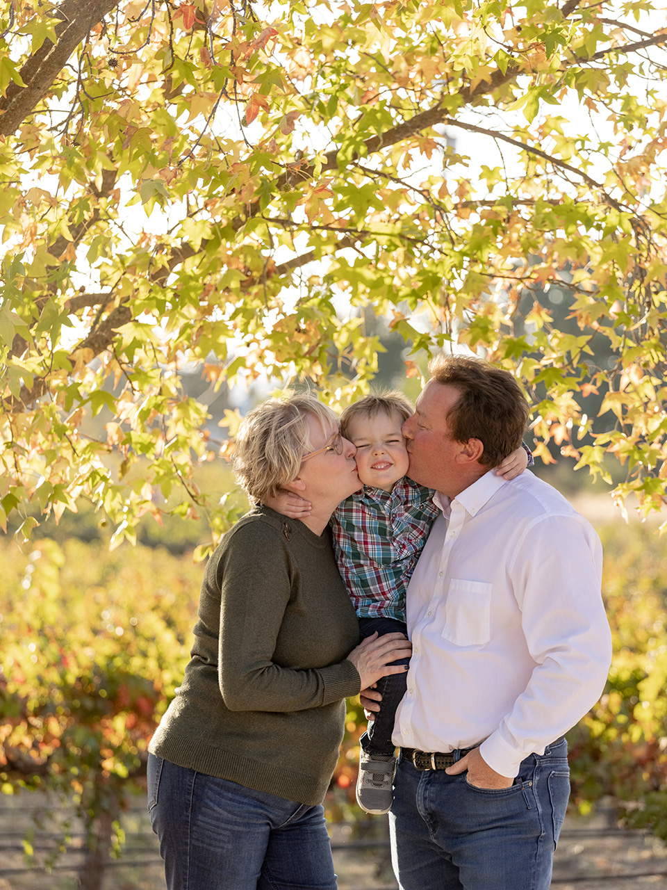Zanoli couple holding child between then and kissing his cheeks